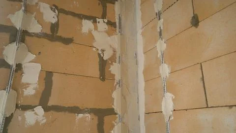 Construction worker applying plaster on a brick wall Foto stock