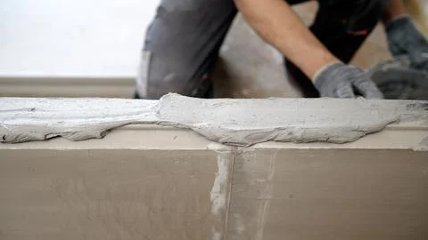Construction worker applying plaster on damaged wall. Stock Photos