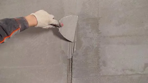 Construction worker applying plaster on a wall using a spatula. Foto stock