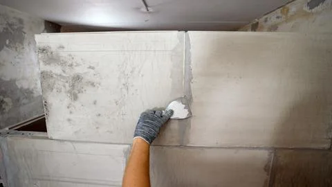 Construction worker applying plaster on the wall. Stock Photos
