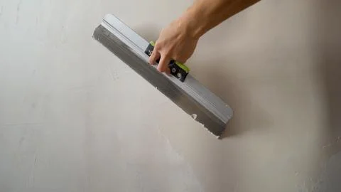 Construction worker applying plaster on wall with spatula Stock Photos