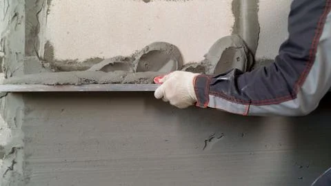 Construction worker applying plaster on wall with trowel Stock Photos