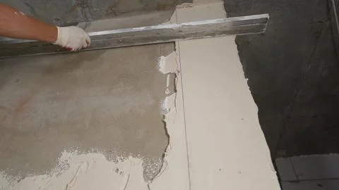 Construction worker applying plaster on the wall using a spatula and leveling Stock Photos