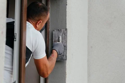 Construction worker applying plaster to a wall around a window during home Stock Photos