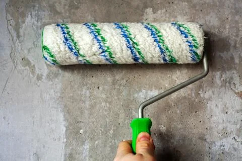Construction worker applying primer with roller brush on wall. Stock Photos