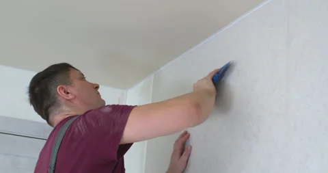 Construction worker applying wallpaper on white wall Stock Footage 306865786