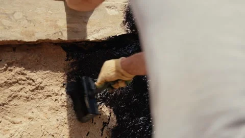 Construction worker applying waterproofing bitumen to a concrete foundation Stock Footage 341294410