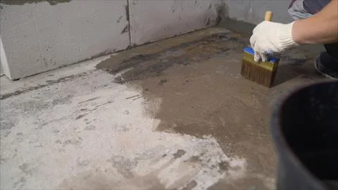 Construction worker applying waterproofing coating on concrete floor with bru Stock Photos