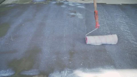Construction worker applying waterproofing membrane on concrete floor 스톡 사진