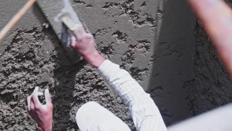 Construction worker applying wet cement plaster on a wall using a wooden float Stock Footage 333487930