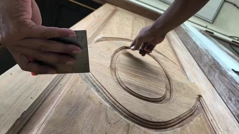 The construction worker is applying wood filler to the surface of the door 库存影片 329492632