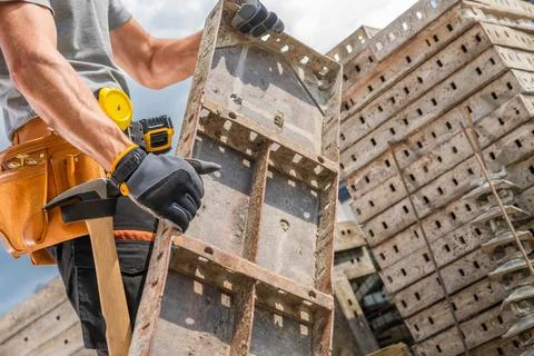 Construction Worker Assembling Building Materials at a Job Site During Midday Foto stock