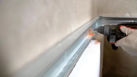 Construction worker assembling metal frame for plasterboard partition wall. C Stock Photos