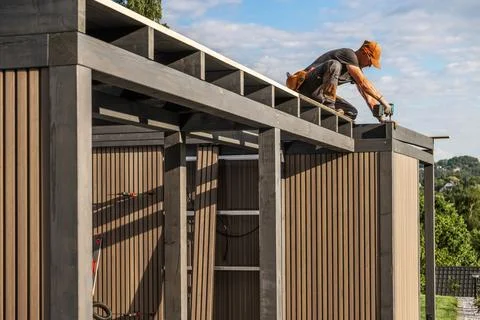 Construction Worker Assembling a Modern Outdoor Storage Shed in a Scenic La.. Photos