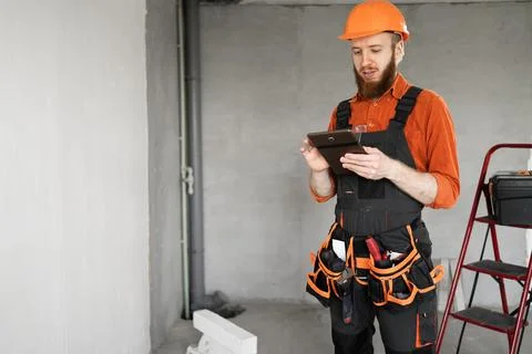 Construction worker bearded man in hardhat using digital tablet at construc.. Stock Photos