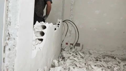 Construction worker with a big sledgehammer hits the concrete wall. Video stock 164489822