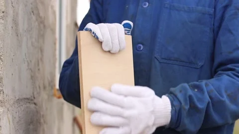 Construction worker in blue overalls holding a wooden board Stock Footage 334625052