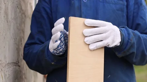 Construction worker in blue overalls holding a wooden board Stock Footage 334626667