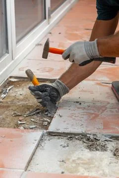 Construction worker breaks and removes old tiles with a hammer and chisel dur Stock Photos