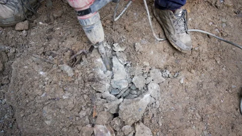 Construction worker breaks a rock with a jackhammer Stock Footage 158979573