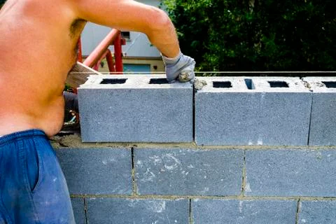 Construction worker bricklayer installing red brick with trowel putty knife o Stock Photos