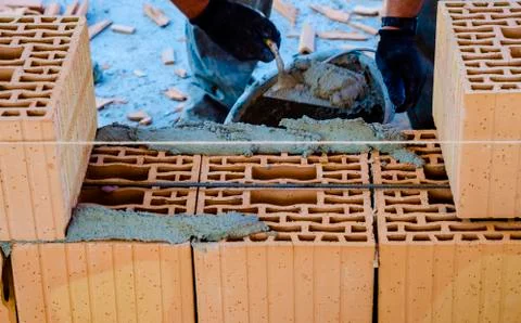 Construction worker bricklayer installing red brick with trowel putty knife o Stock Photos