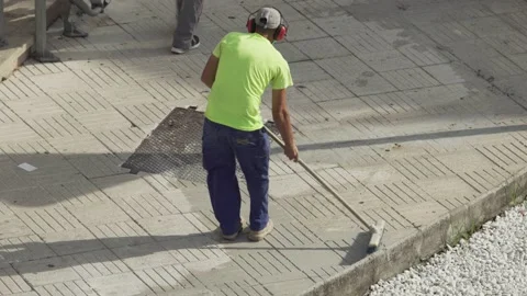Construction worker with broom working on a sidewalk Видео 139485233
