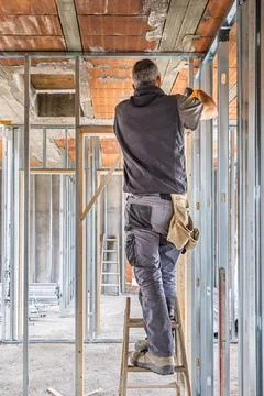Construction worker building new interior metal frame walls Stock Photos