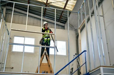 Construction worker building plasterboard wall in building under construction Stock Photos