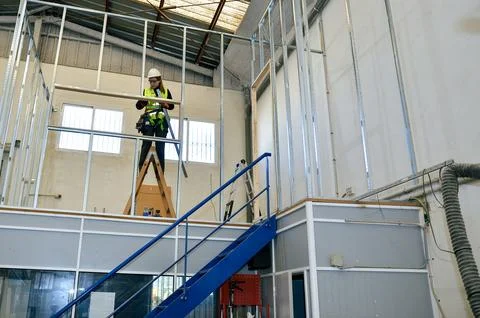 Construction worker building plasterboard wall in industrial building Stock Photos