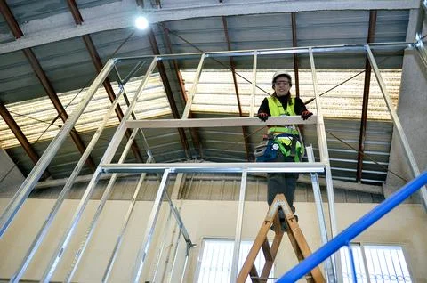 Construction worker building plasterboard wall with metal frame Stock Photos