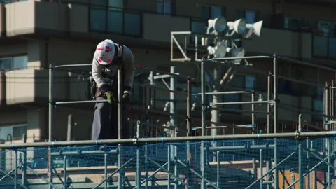 Construction worker on a building site in Japan with a spanner on scaffolding Video stock 130375984