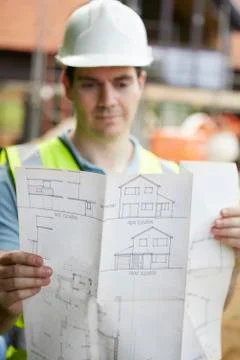 Construction worker on building site looking at house plans Stock Photos