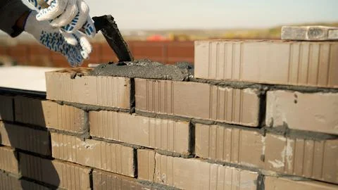 Construction worker building a wall with bricks and mortar Stock Photos