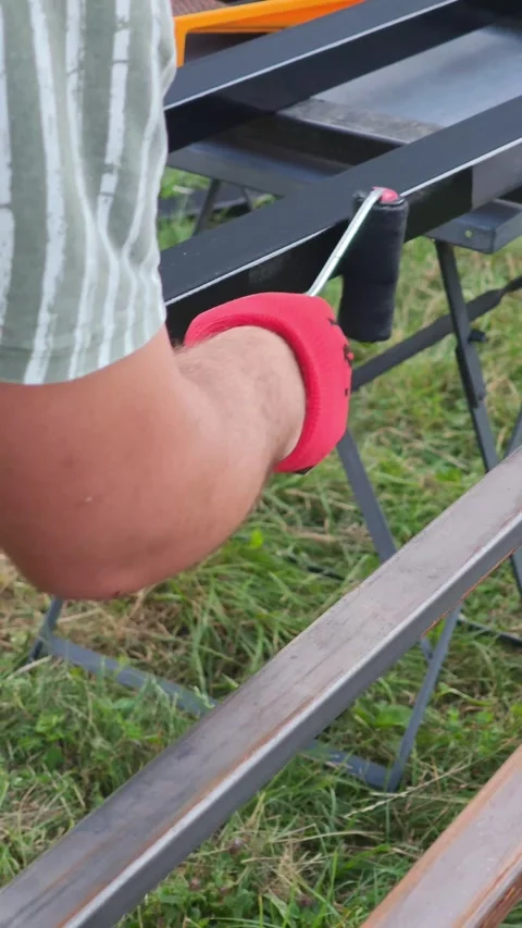 Construction worker carefully applying black protective coating on long metal Vidéo 315356049