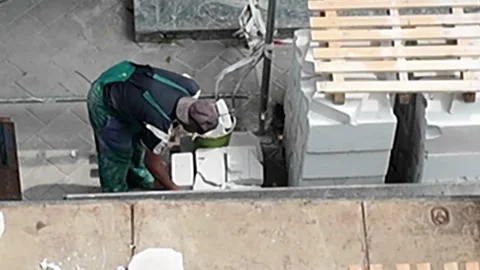 Construction worker carefully stacking concrete blocks on a sunny day Stock Footage 338332930