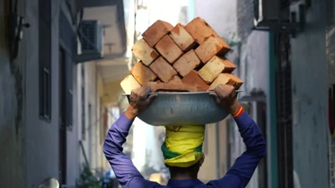 Construction Worker Carrying Bricks on Head at Urban Building Site Stock Footage 327551651
