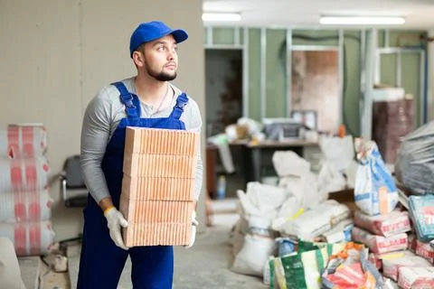 Construction worker carrying bricks at renovating object Stock Photos