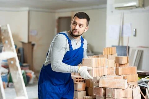 Construction worker carrying bricks at renovating object Stock Photos