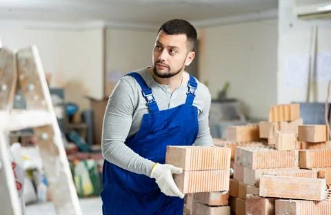 Construction worker carrying bricks at renovating object Stock Photos
