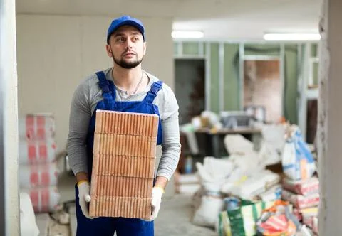 Construction worker carrying bricks at renovating object Foto stock