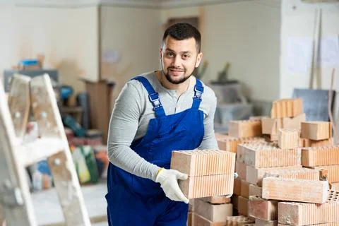 Construction worker carrying bricks at renovating object Stock Photos