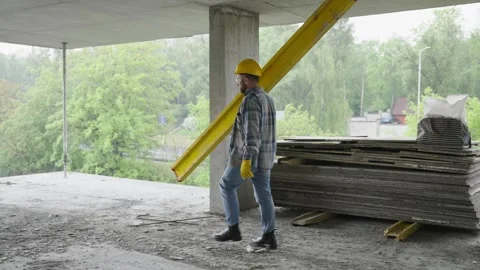 Construction worker carrying heavy beam on building site Video stock 337467763