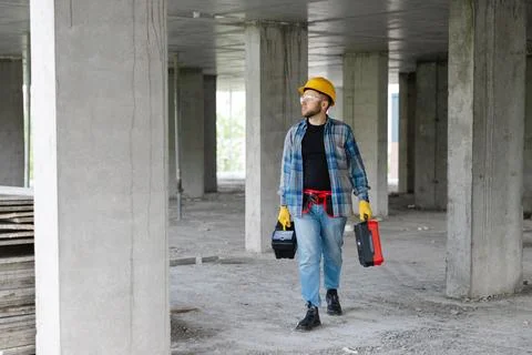 Construction worker carrying toolboxes walking on site Stock Photos