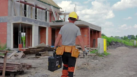 Construction Worker Carrying Tools at a Building Site in Bright Daylight Stock Footage 314512032