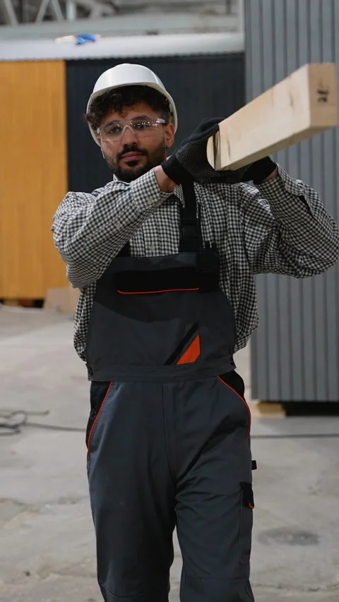 Construction worker carrying wooden plank in factory Stock Footage 313091853