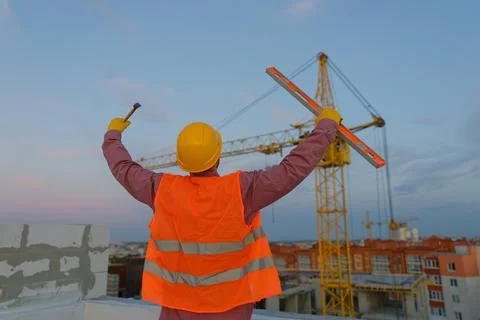 Construction worker celebrating with level and hammer at building site Stock Photos
