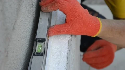 Construction worker check the level of insulation sheets on house facade wall Stock Footage 194312671