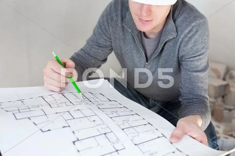 A Construction Worker Checking Documents With Pencil In His Hand