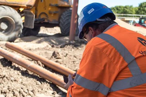 Construction worker checking his mobile phone on a building site Stock Photos